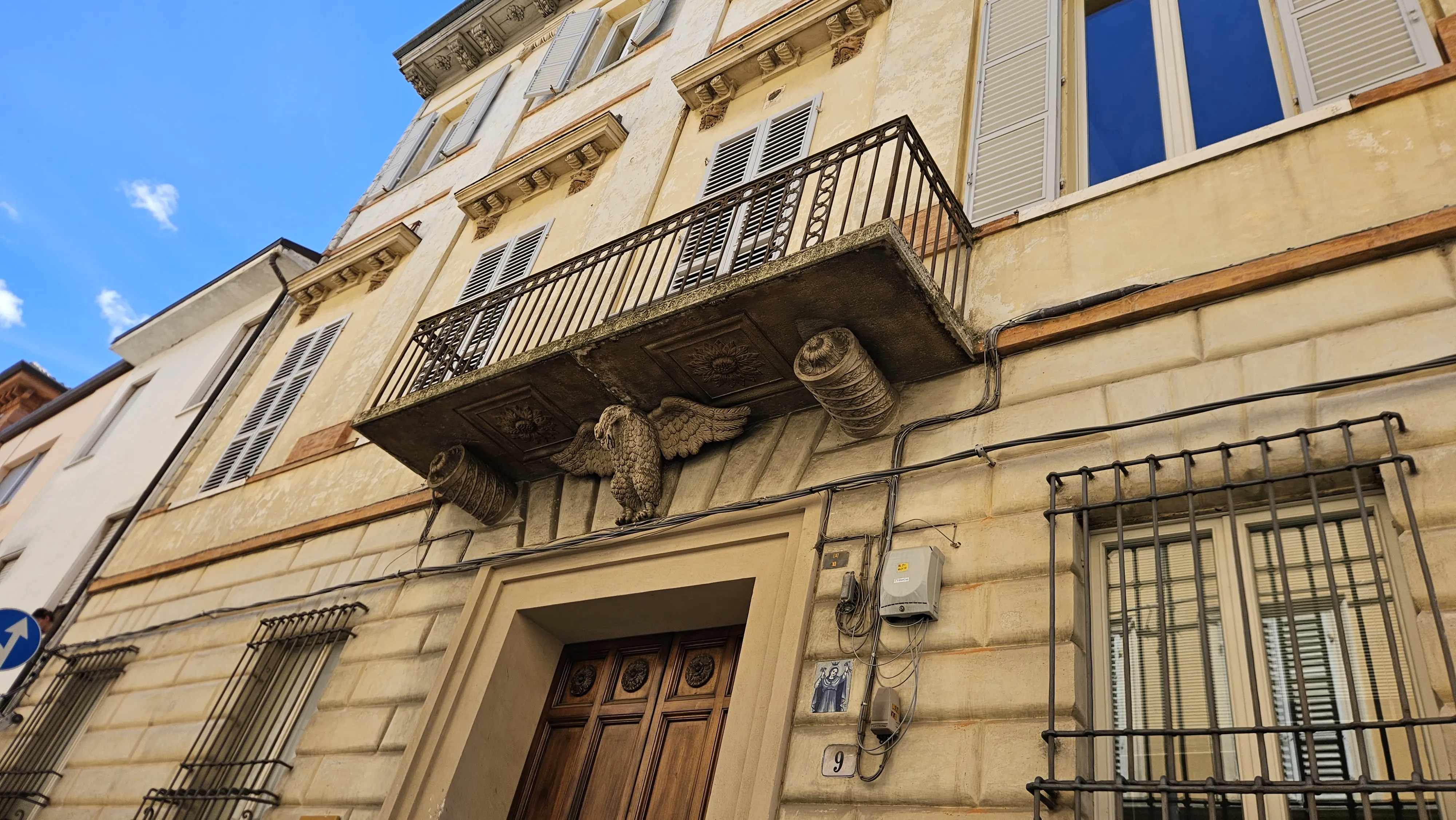 Palazzo storico con aquila scolpita e balcone in ferro battuto, centro storico di Faenza